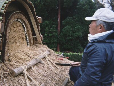 Master craftsman Shigeo Suzuki shaping the ridge detail of a thatched roof in Japan