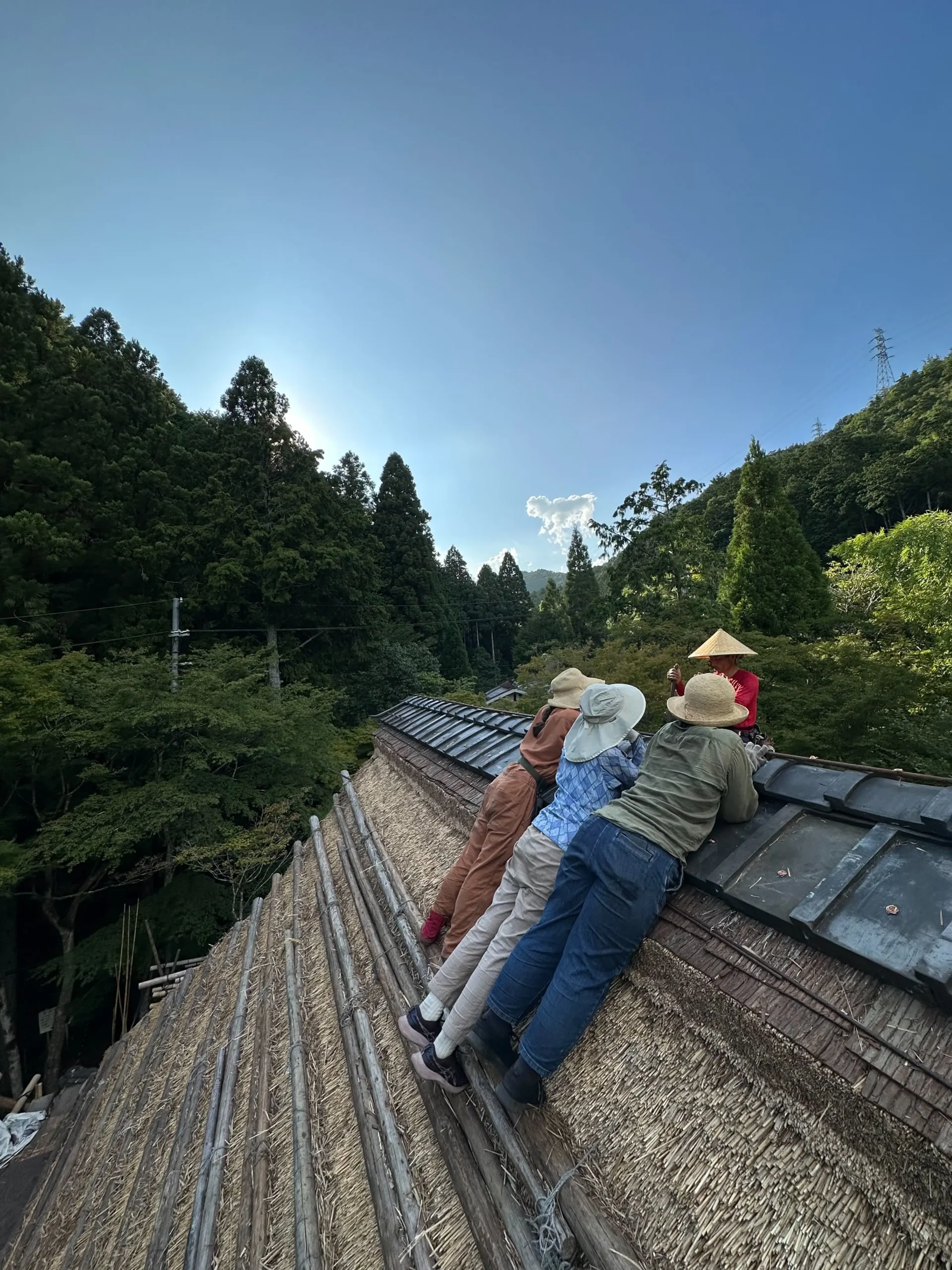 Young apprentice watching Haruo Nishio working on a traditional thatched roof