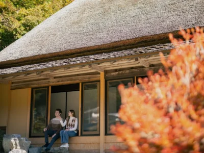 Guest sitting on the engawa porch of Obatake thatched house Miyama Kyoto